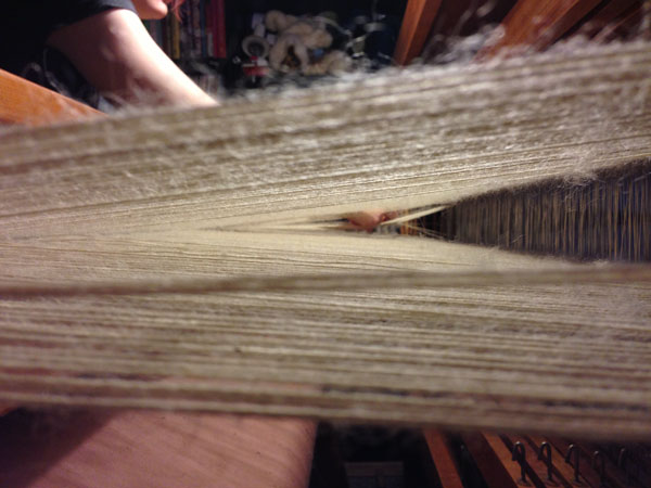 Undoing- by hand, the fuzzies that have been produced by the friction of the reed and the change of harnesses.