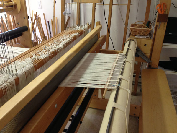 One method of how to attach the warp to the front beam. Another method would be to lay the warp threads directly on the sandpaper beam to limit the amount of waste used to tie on.