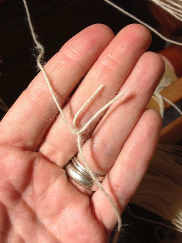 I then pull on the new warp thread so that the loop tightens around the old warp thread. I then pull on both long ends to fully tighten the knot.